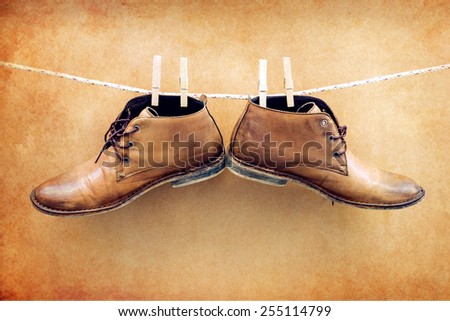 Brown boots hanging on rope over brown background