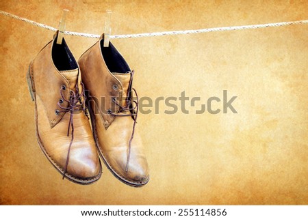 Brown boots hanging on rope over brown background