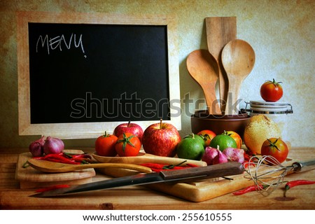 Still life with blackboard and vegetables on a wooden table over wall grunge background