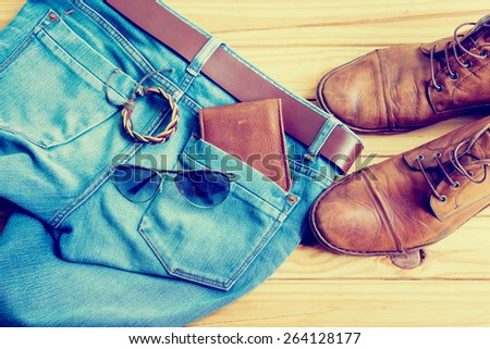 Still life with blue jeans and boots on wooden background