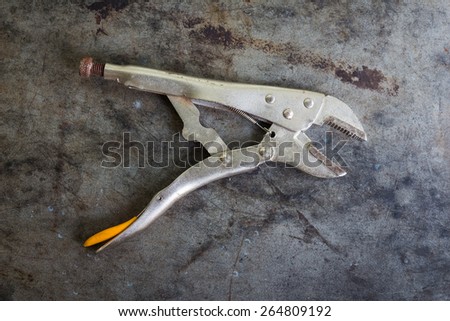 Still life with old locking plier on on table grunge background, top view