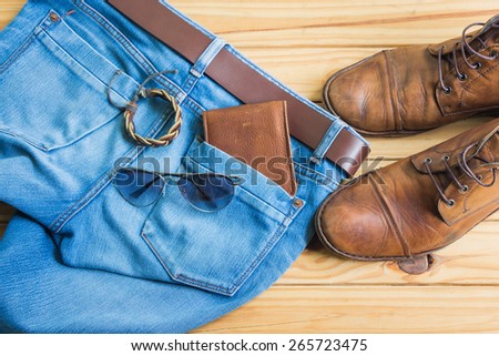 Still life with blue jeans and boots on wooden background