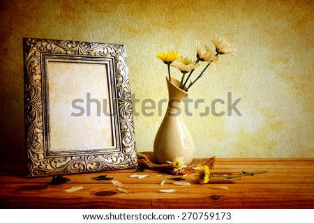 Vintage photo frame and flowers on wooden table over grunge background, Still life style