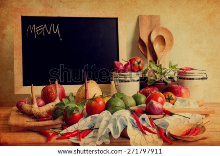 Still life with blackboard and vegetables on a wooden table over wall grunge background