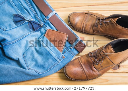 Blue jeans and boots on wooden background