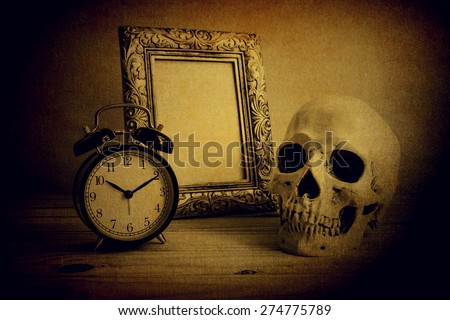 Still life with vintage photo frames, vintage clock and skull on wooden table over grunge background