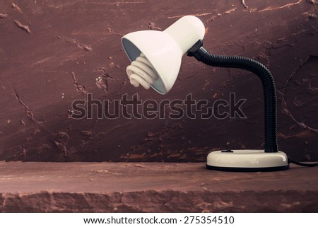 White desk lamp on brown stone table over stone grunge background.