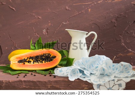 Ripe papaya with green leaf on brown stone table over stone grunge background.
