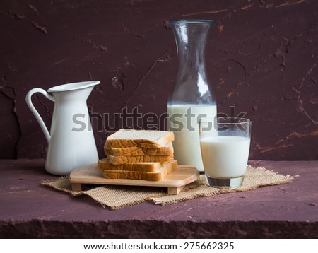 Milk with whole wheat bread on brown stone table over stone grunge background.