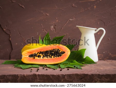 Ripe papaya with green leaf on brown stone table over stone grunge background.