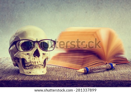 Still life with skull, old book and pencil on wooden table over grunge background