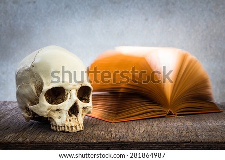 Still life with skull and old book on wooden table over grunge background