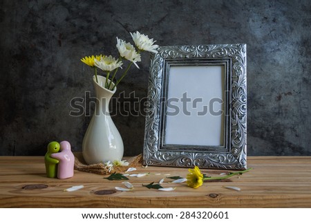 Vintage photo frame and flowers on wooden table over grunge background, Still life style