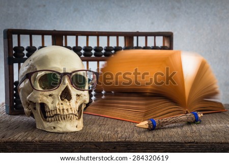 Still life with skull, old book,abacus and pencil on wooden table over grunge background