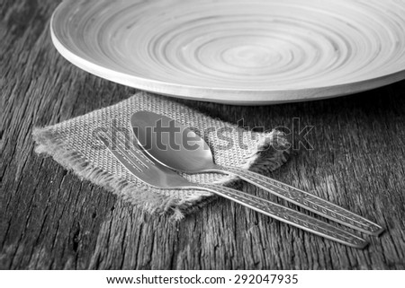 Fork and spoon with plate on wooden dining tables, rustic style, Black and white