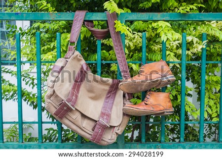 Men's casual outfits with boots and bag hanging on tree background