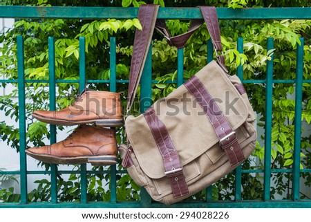 Men\'s casual outfits with boots and bag hanging on tree background
