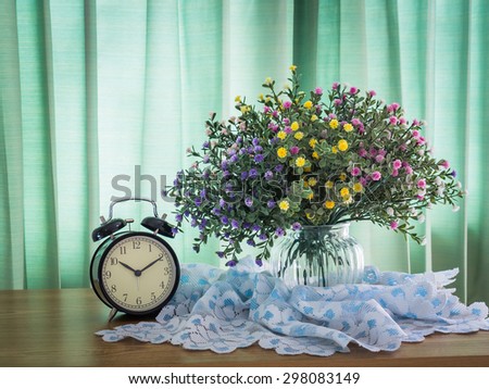 Bouquet of flowers with vintage clock on a wooden table over green curtain background in the bedroom
