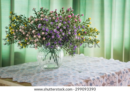 Bouquet of flowers on a wooden table over green curtain background in the bedroom