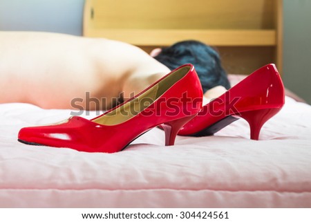 Red high heel shoes with the man sleeping on the bed