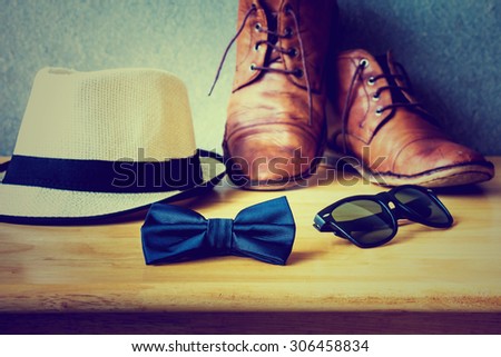 Men\'s casual, bow tie with sunglasses and boots on wooden over wall grunge background
