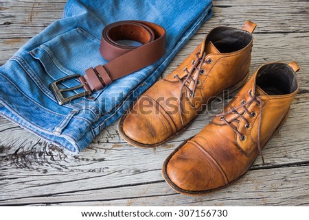 Blue jeans and boots on wooden background
