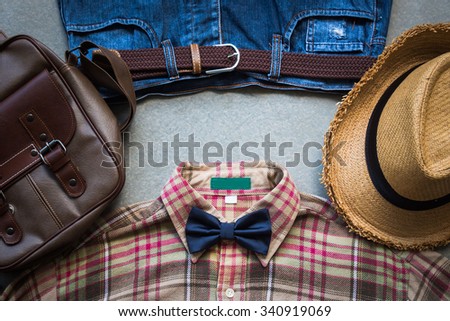 Men\'s casual outfits background, brown plaid shirt, bow tie, blue jeans and brown bag on grunge background