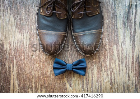 Men\'s casual outfits with brown shoes and blue bowtie on rustic wooden background