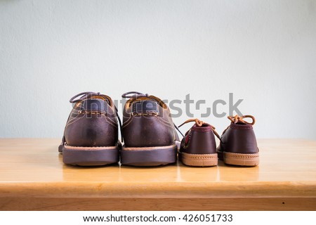 Brown shoes of daddy and son on on wooden table, bar or counter over gray wall background, fathers day
