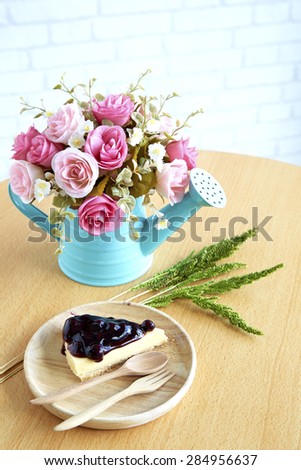 Blueberry Cheesecake With a vase of roses on the table