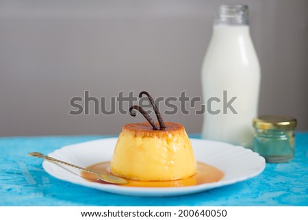 Creme Caramel with Vanilla Beans on Top. Milk Bottle and a Small Jar in the Background