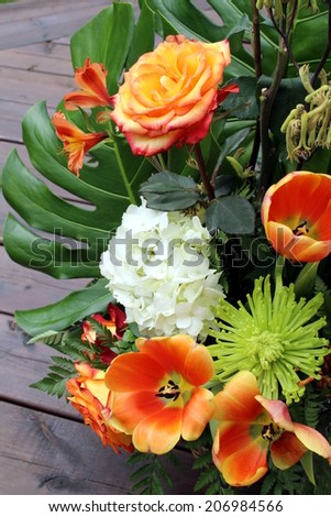 Floral arrangement of tulip, rose, hydrangea, lily, chrysantheme and leave of monstera deliciosa