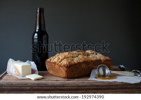 Homemade beer bread with honey and butter on cutting board