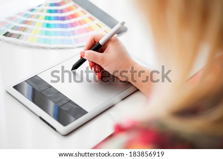 Graphic designer working on a digital tablet in the background with palette