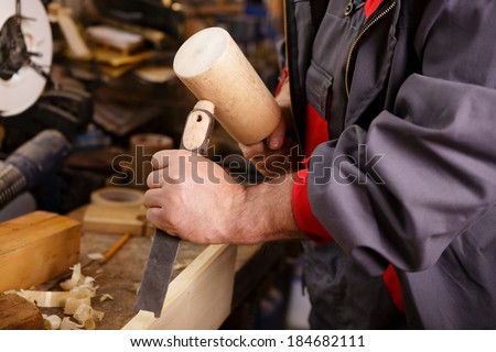 Hands carver at work with a wooden hammer and chisel
