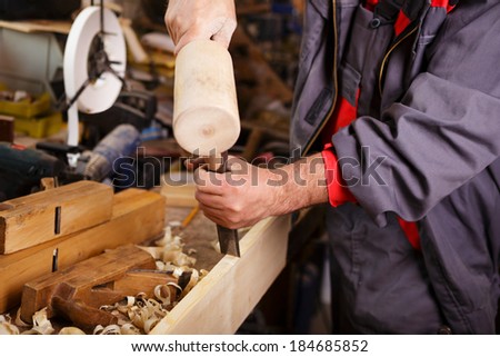Hands carver at work with a wooden hammer and chisel