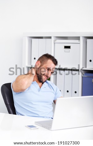 Young businessman has pain of the cervical when working with laptop in office