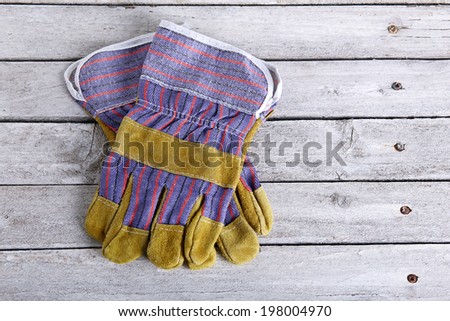 Top view of a leather work gloves lying on a wooden plate