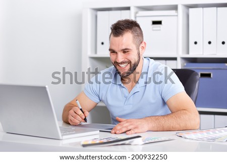 Happy graphic designer using a graphics tablet in a modern office