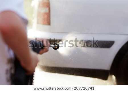 Man washing his car with using a high pressure water jet