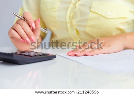 Woman\'s hands with a calculator and a pen in office