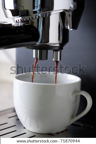 Espresso coffee maker in action with white cup