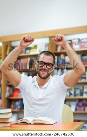 Happy man in the library works and studies
