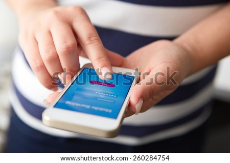 Female hands using mobile banking on white smartphone