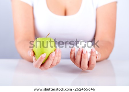 Woman is holding a sugar cubes and in his other hand apple