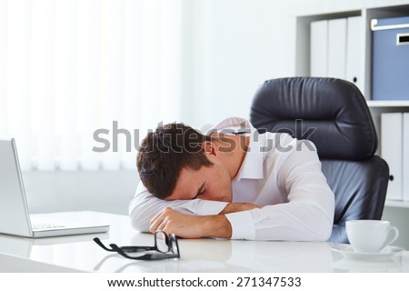 Young businessman in white shirt sleeping on desk in the office