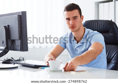 Young man in office holding coffee cup