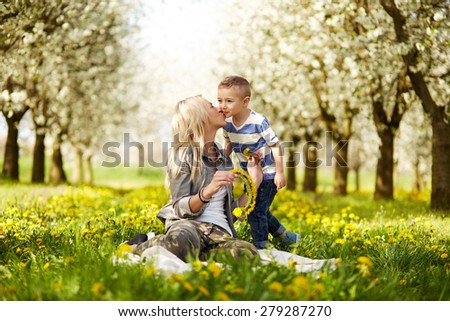 Mother kisses her son in blooming orchard