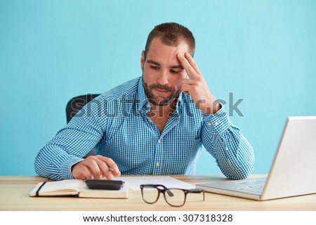 Pensive businessman calculates taxes at desk in office