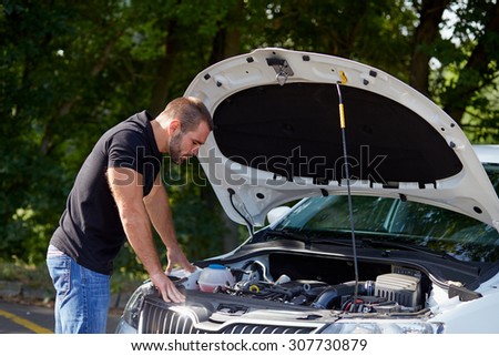 Young man standing in front of a broken car
